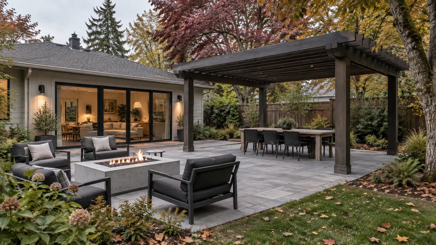 Fictional backyard patio with gray stone, a dark pergola, lounge seating and early autumn foliage